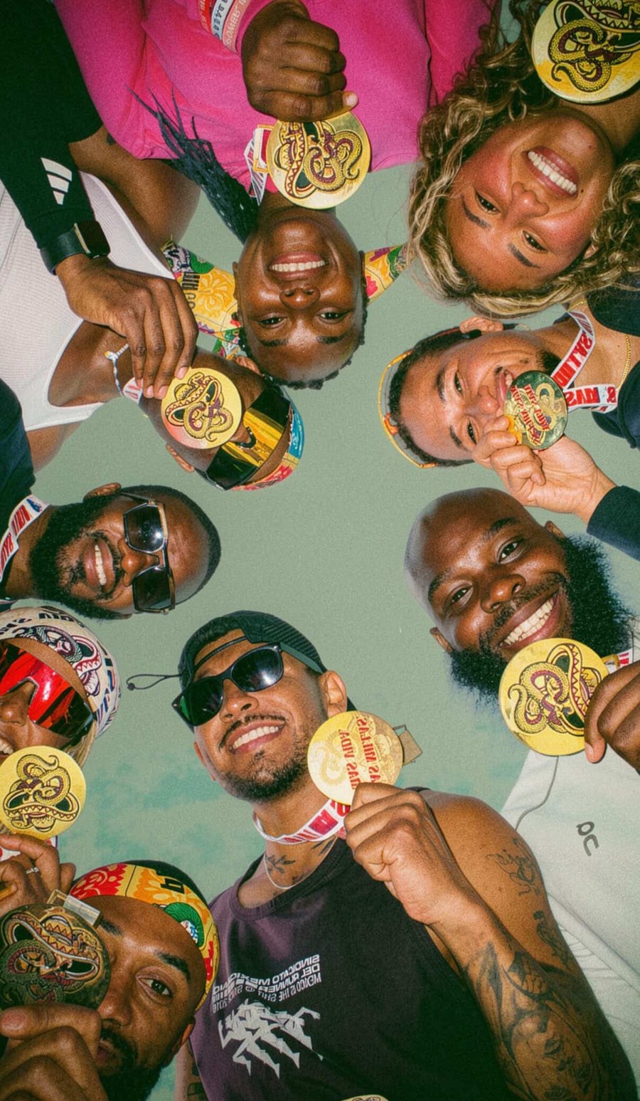 Run club friends huddled in a circle showing off their race medals